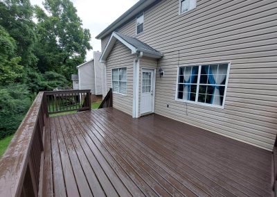 Completed large dark composite deck built by Bystone attached to a residential home with vinyl siding in Birmingham, AL.