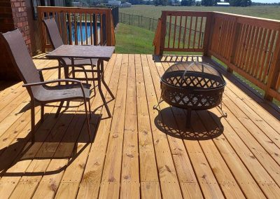 Custom pressure-treated wood deck patio built by Bystone in Birmingham, AL, decorated with a small fire pit and outdoor seating.