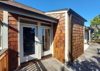 Home exterior renovation by Bystone in Birmingham, AL, featuring natural wood siding and a white glass patio entry door.