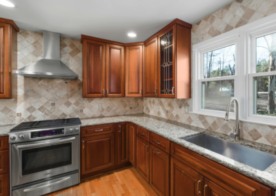 Kitchen remodel by Bystone in Birmingham, AL, featuring dark wood cabinets, granite countertops, and a stone tile backsplash