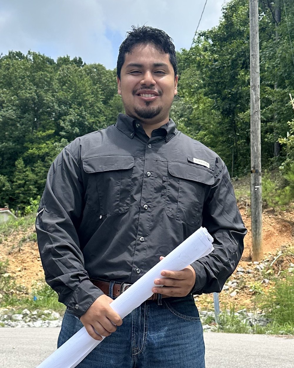 Brandon from Bystone holding construction blueprints on site.
