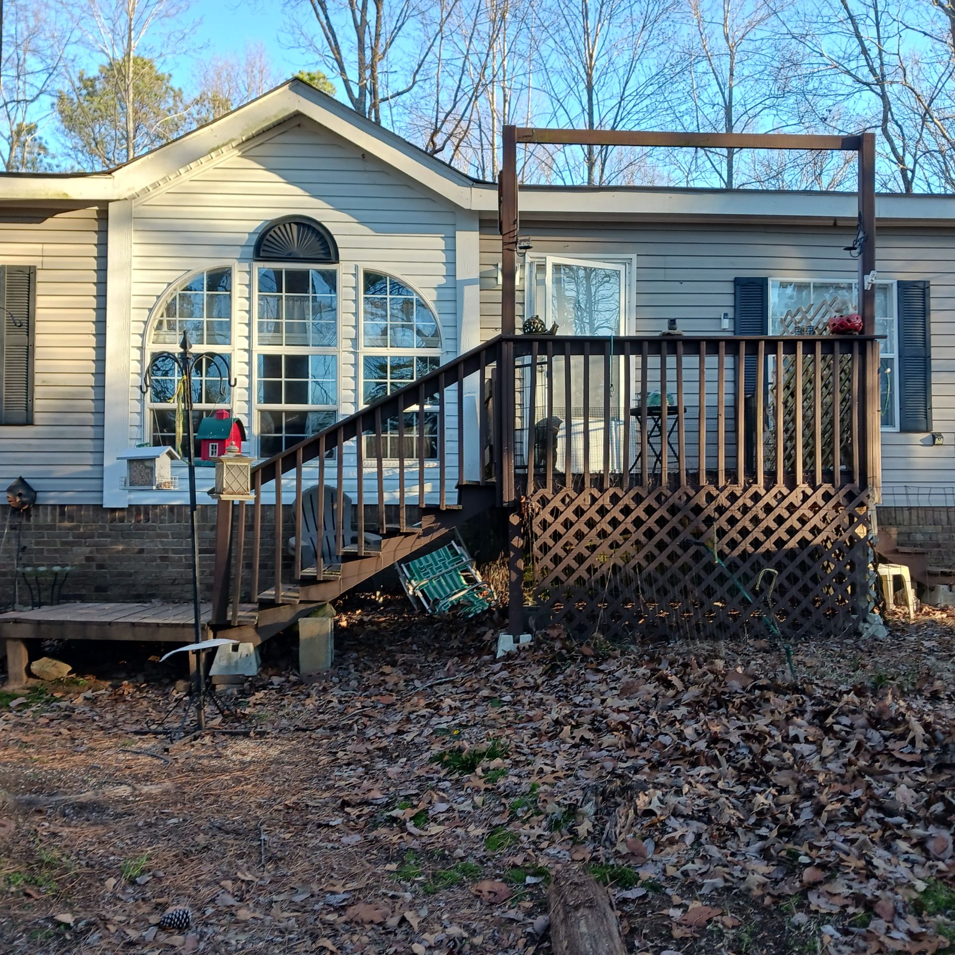 Before photo of a residential home deck remodel project by Bystone, featuring a weathered wooden porch and outdated lattice skirting in the Logan Martin Lake and Pell City area.