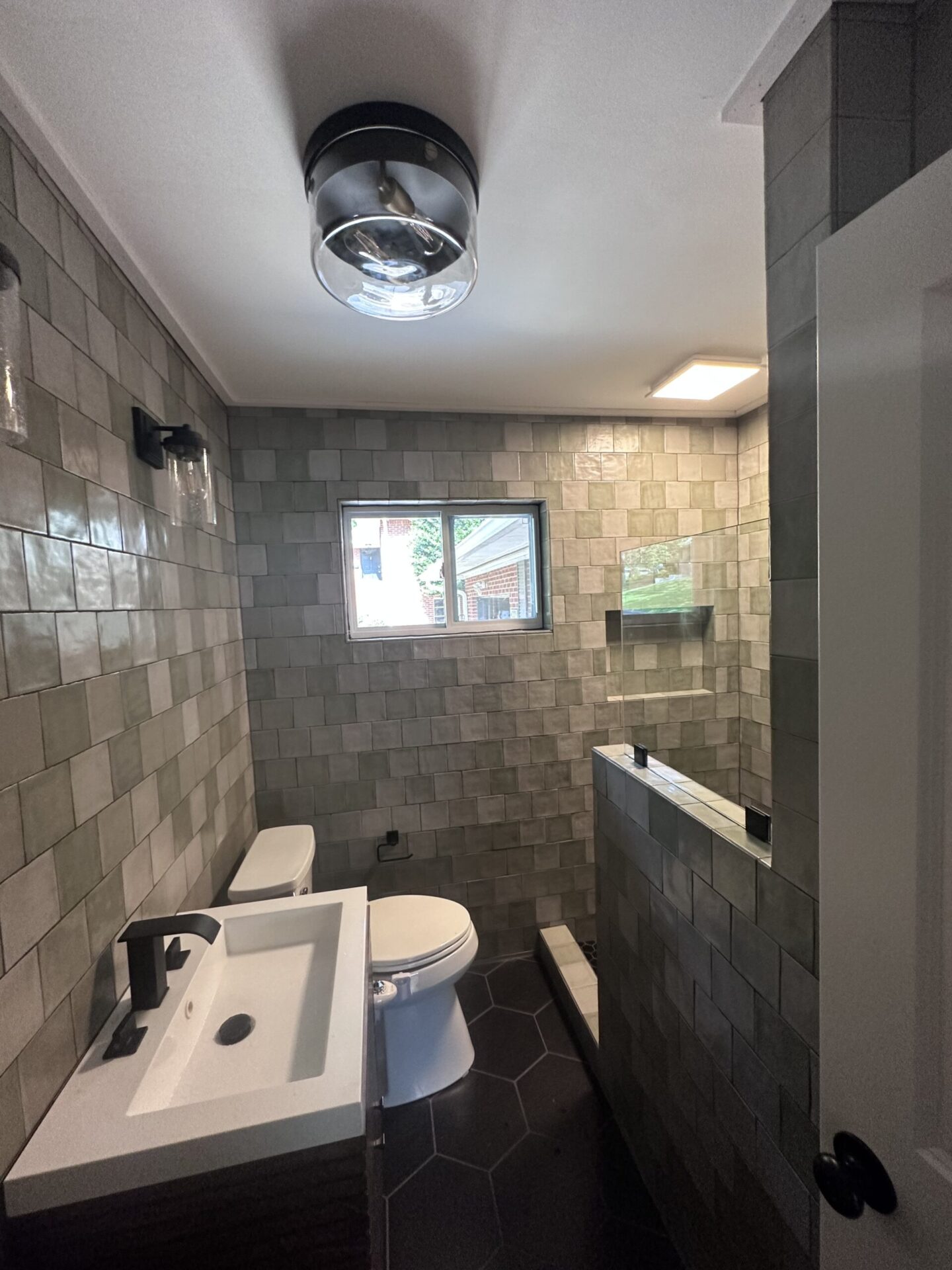 Bystone residential contracting project entry showing the completed bathroom remodel in Hoover, Alabama. Image highlights the new custom shower, imported floating vanity, upgraded lighting fixtures, and high-end finished flooring installed by Miguel and the team.