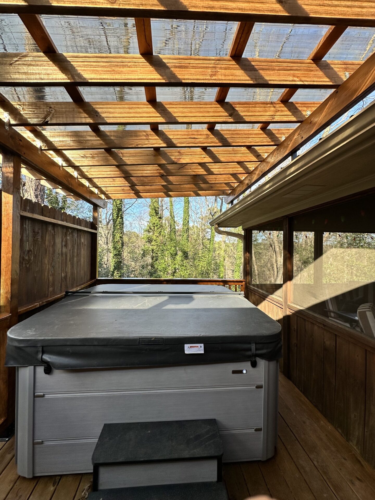 Completed luxury backyard deck environment featuring integrated hot tub and modern timber pergola